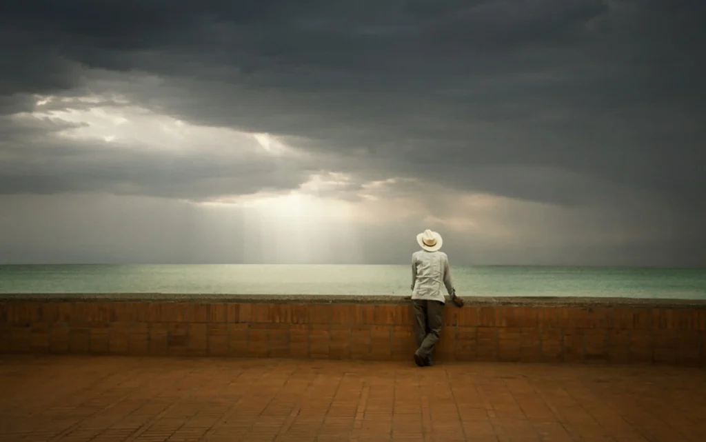Pessoa sentada em silêncio, em ambiente calmo, representando permanência e estabilidade interior.